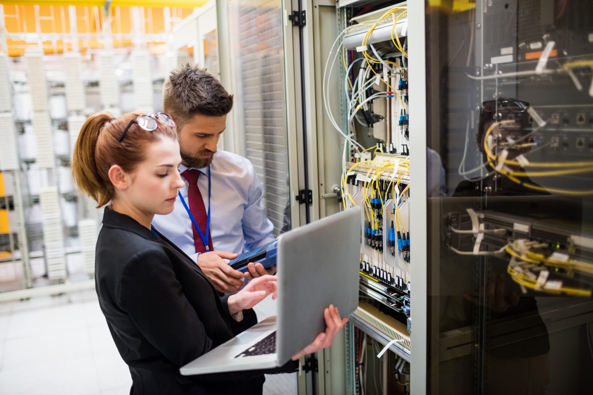 Technicians using laptop while analyzing server Technicians using laptop while analyzing server
