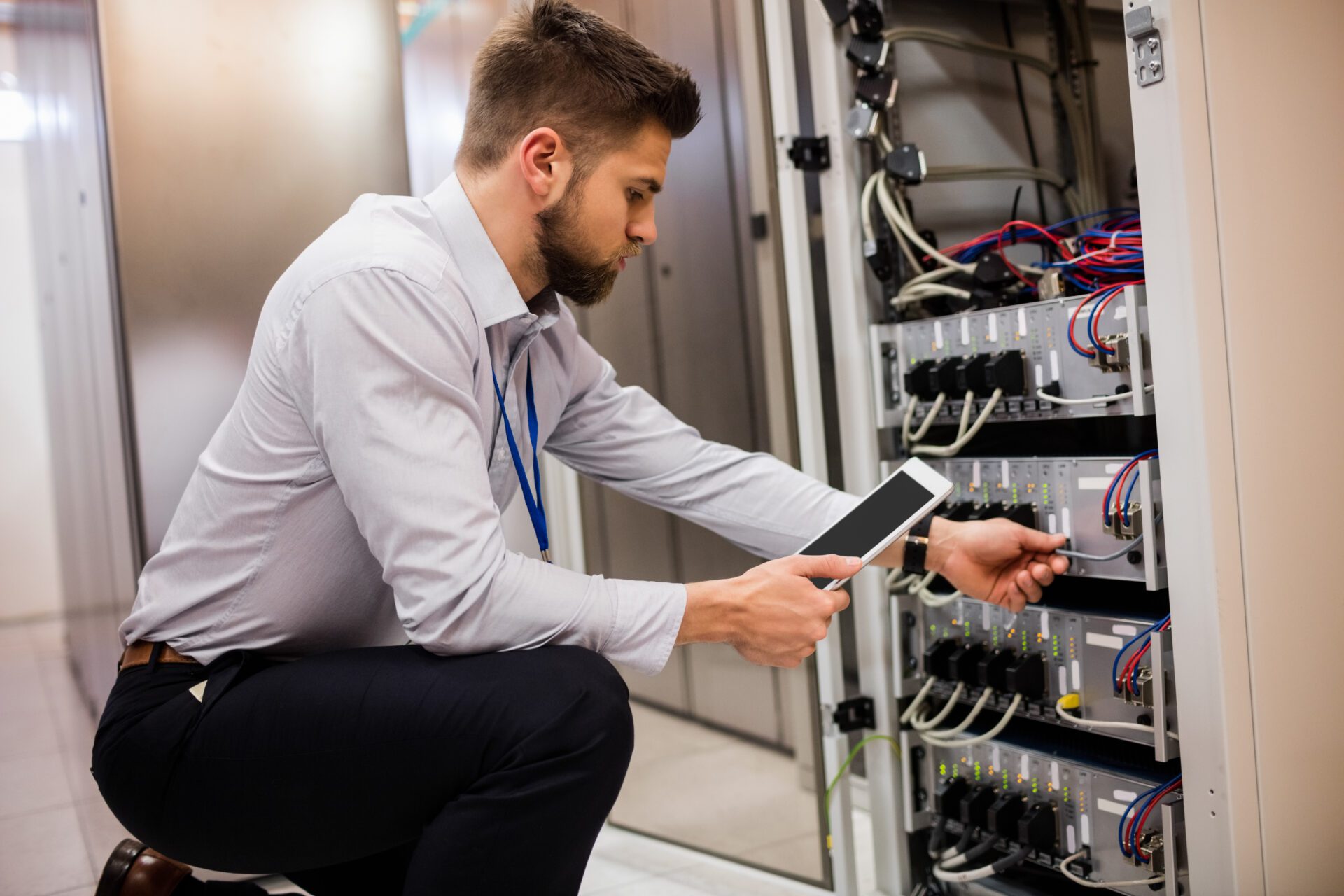 Technician using digital tablet while analyzing server Technician using digital tablet while analyzing server in server room